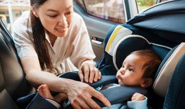 Mom putting baby in car seat